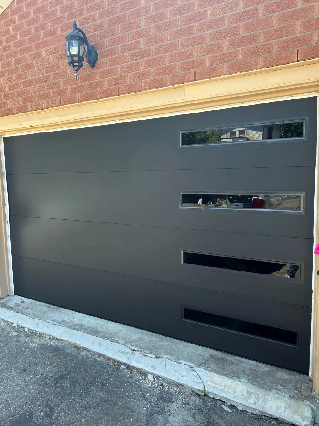Black modern garage door with glass strips on a Toronto-style brick home