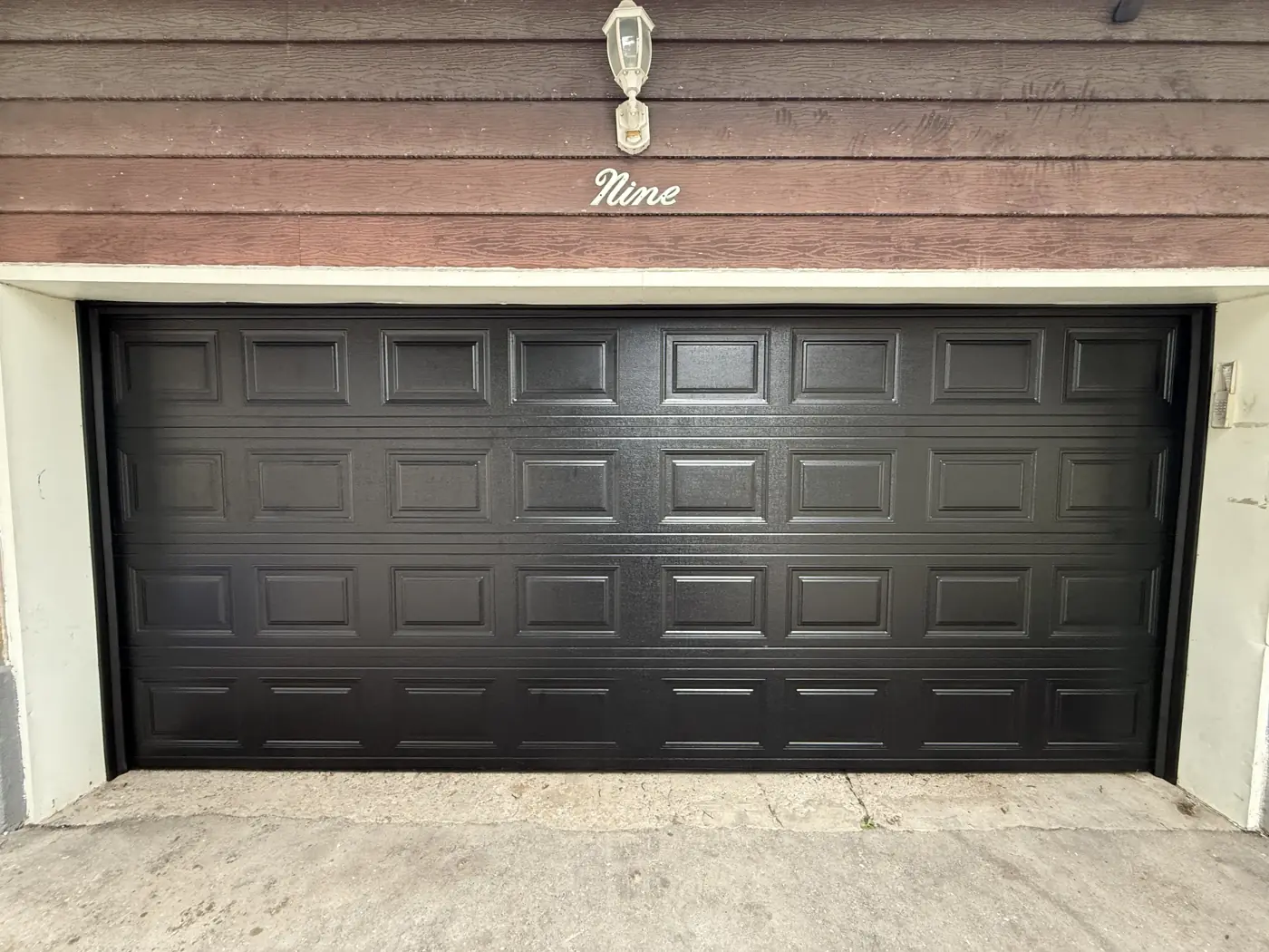 Dark brown garage door on a brick home, a door like those our team services across the GTA
