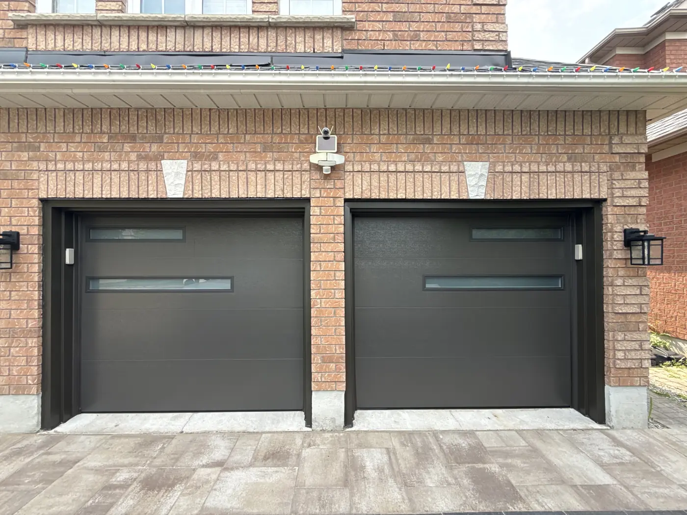 Two modern black garage doors on a brick home, the kind of door our team installs and repairs across the GTA